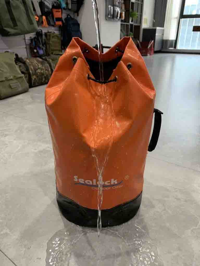 Water running straight through the drawstring opening of a stuff sack, showing it is not waterproof